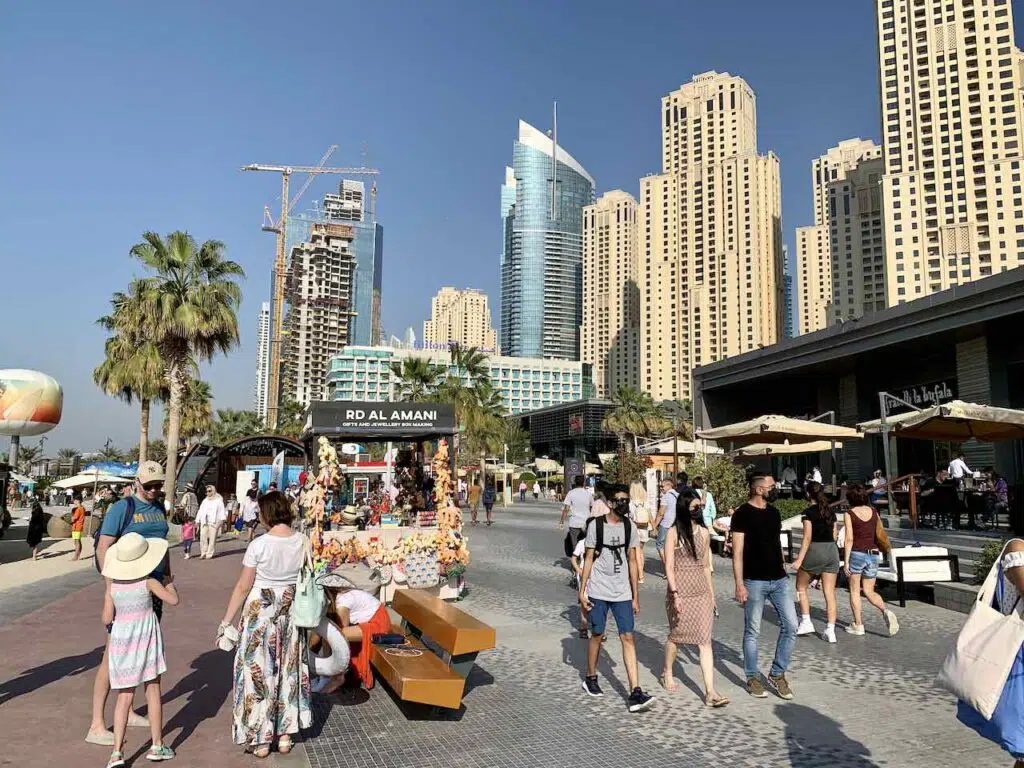 Dubai Marina Beach Walk with waterfront buildings and people walking.