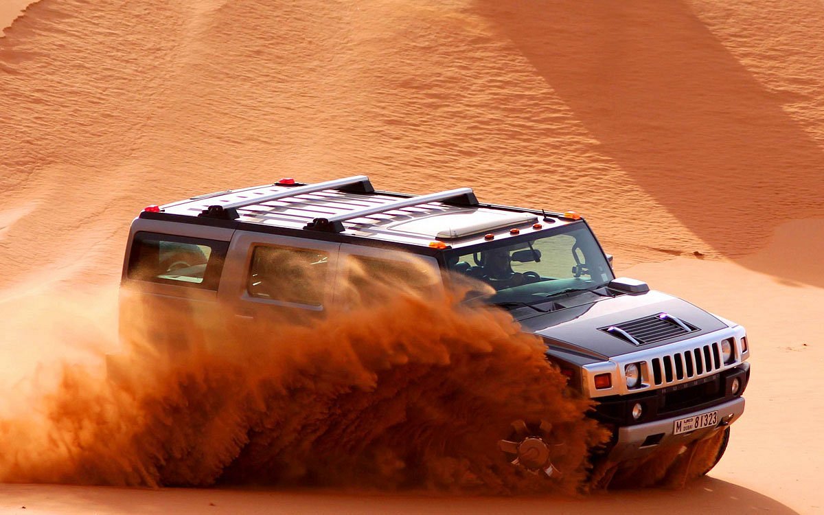 Hummer driving over red desert dunes during Dubai safari tour